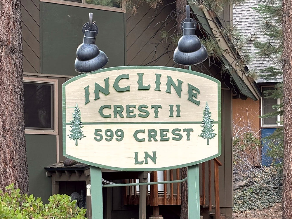 Incline Crest II entry sign with raised green letters and pine trees on a shaped panel between two wood posts