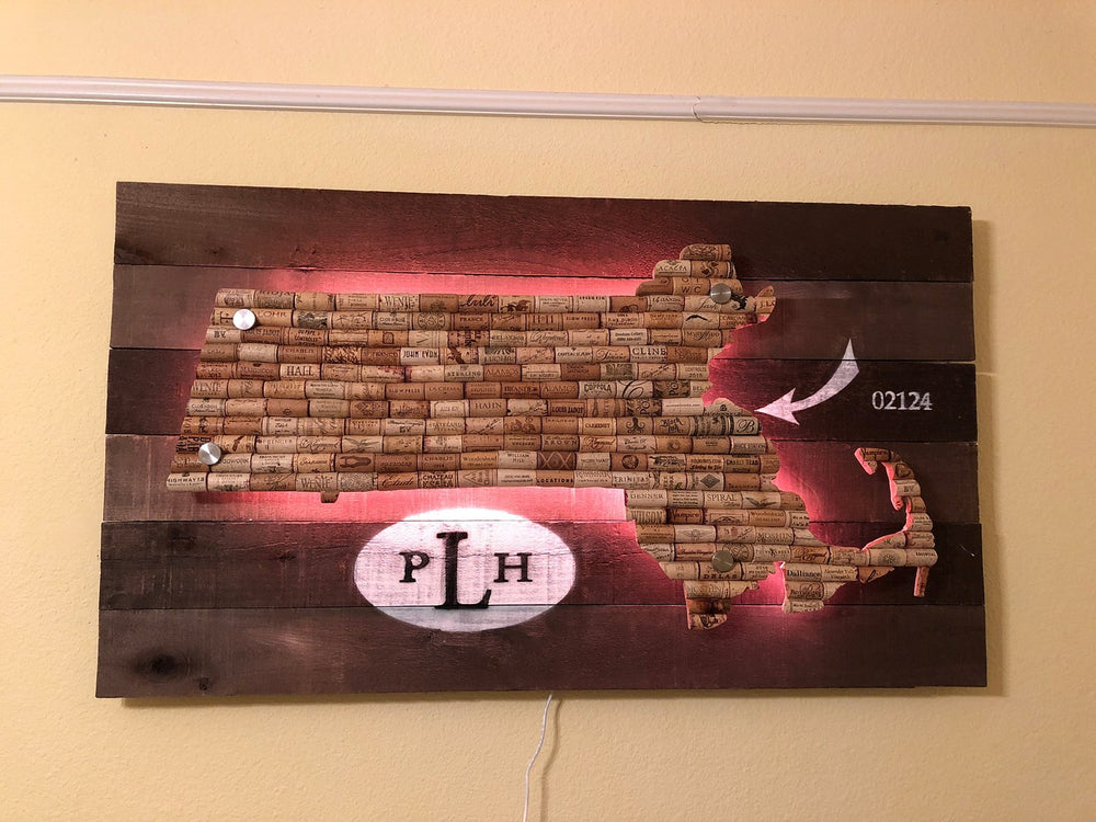 Map of Massachusetts made from wine corks on a recycled barn wood sign, with the PLH logo and an arrow pointing to 02124