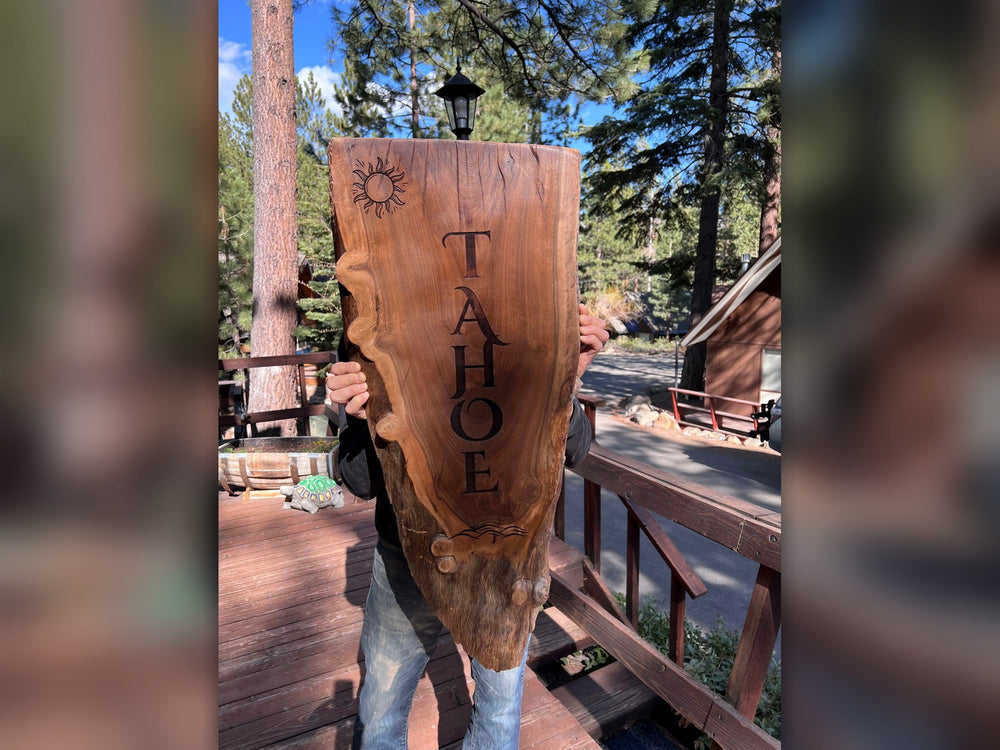 Live-edge wood slab engraved with the word TAHOE, a sun and waves